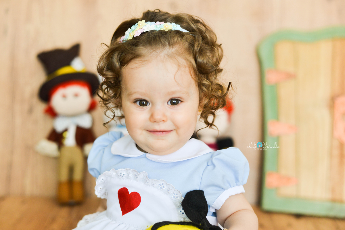criança sentada, sorrindo vestida de Alice no país das maravilhas acompanhamento mensal  fotografico em Maringá