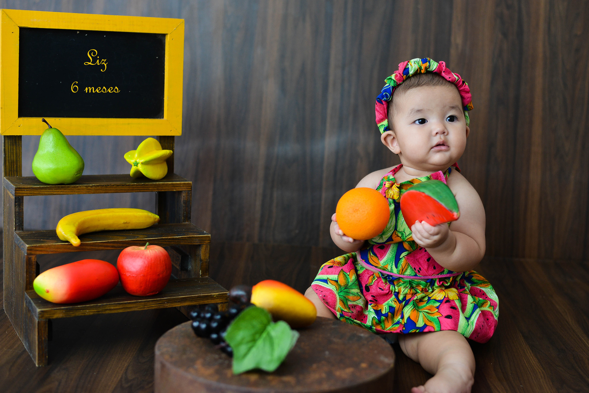 fotografia de bebe no estudio em Maringá segurando laranja 