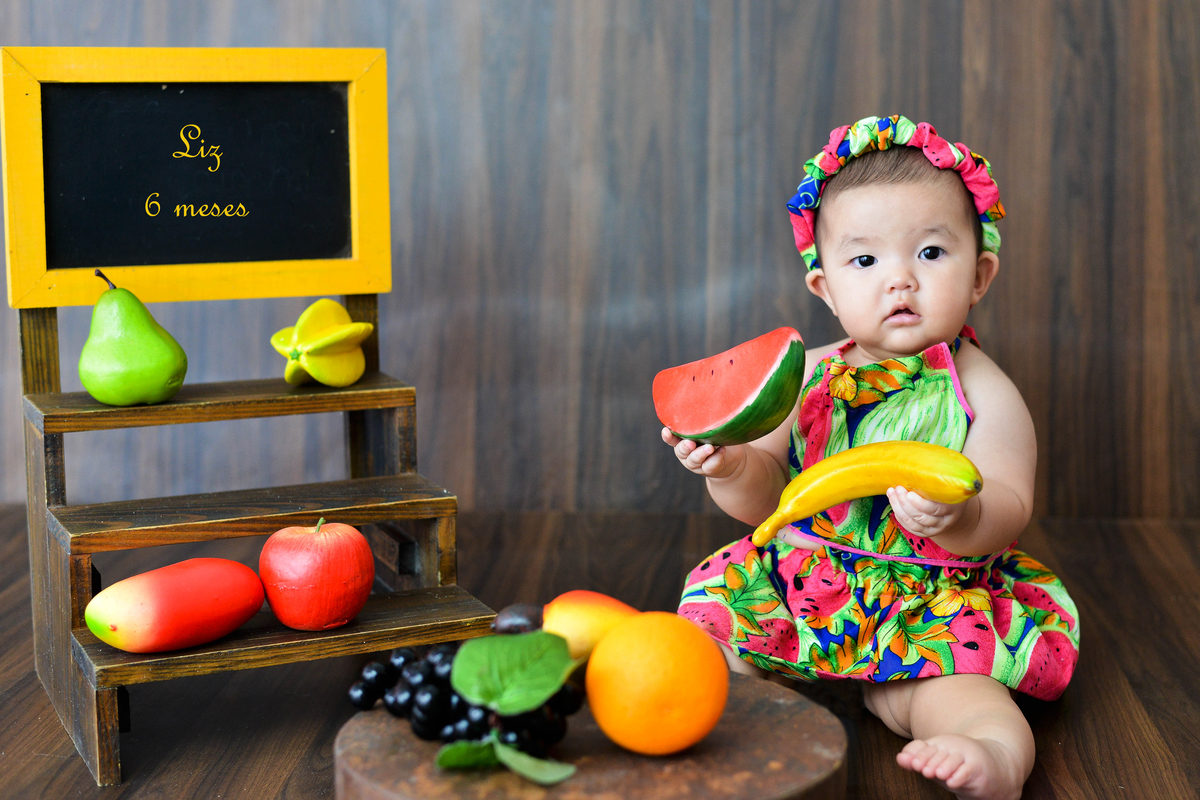 fotografia de bebe no estudio em Maringá com banana na mao 