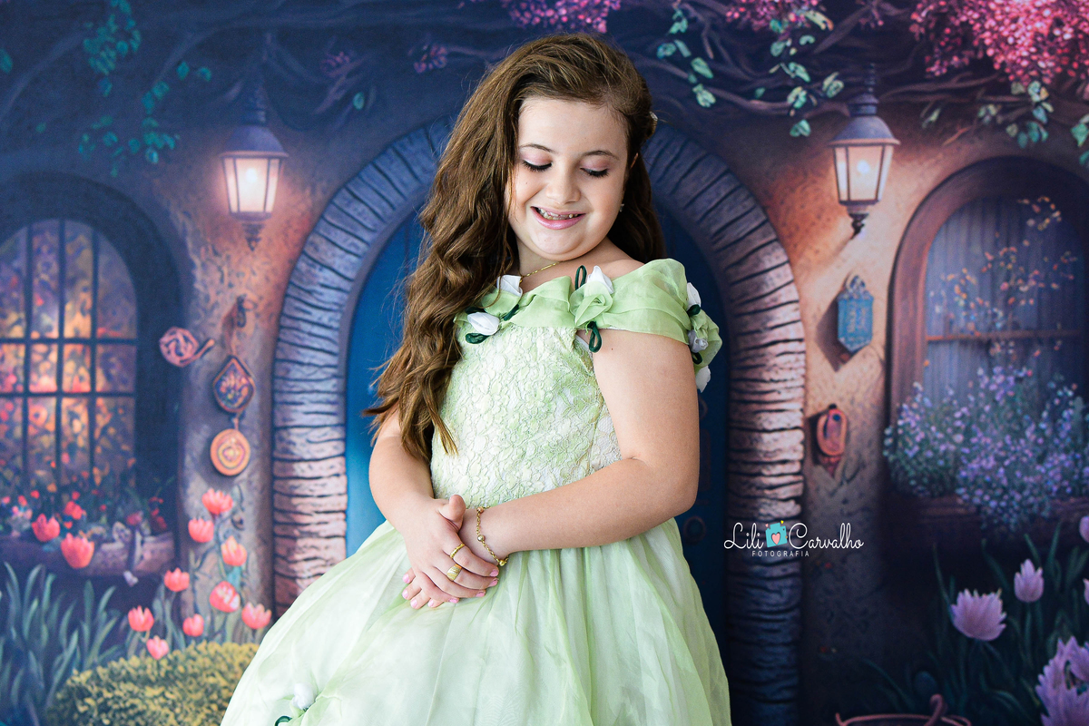 Foto de menina no estudio em Maringá,. vestido verde, tema páscoa,  olhando para baixo e sorrindo 