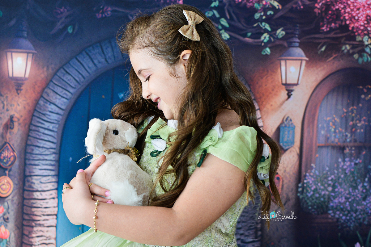 Foto de menina no estudio em Maringá,. vestido verde, tema páscoa,  abraçando coelhinho 