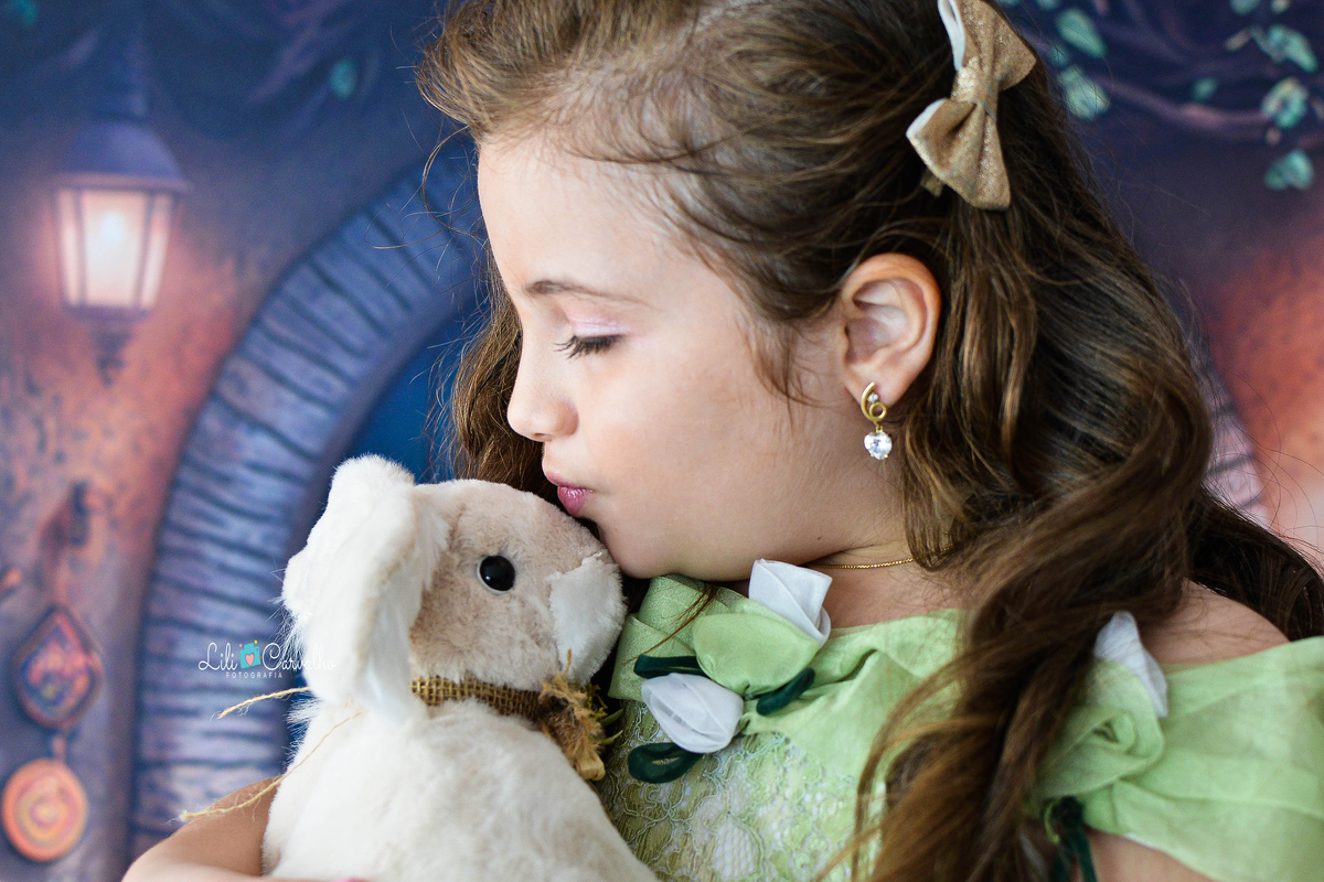 Foto de menina no estudio em Maringá,. vestido verde, tema páscoa,  beijando o coelhinho 