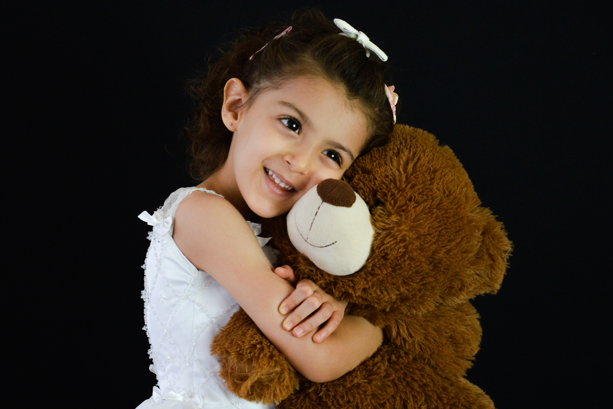 Fotografia de menina feita no estúdio em Maringá  abraçando ursinho 