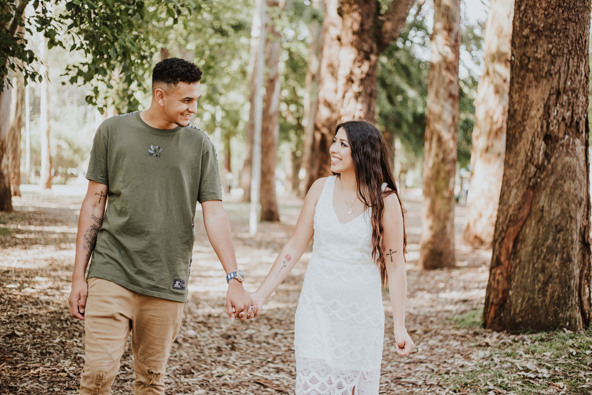 casal andando de mãos dadas no parque e se olhando