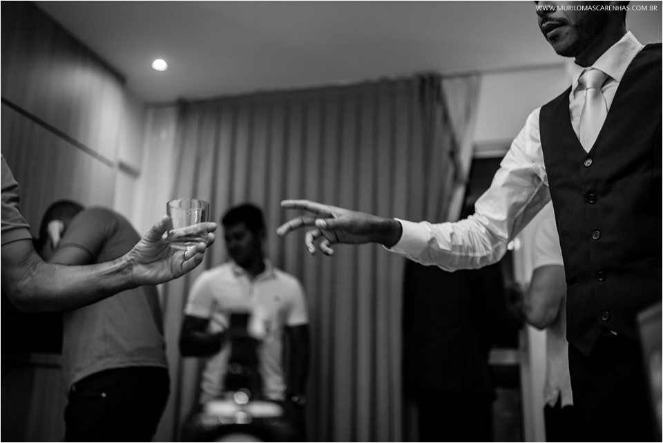 noivo de colete de terno pegando copo de uisque