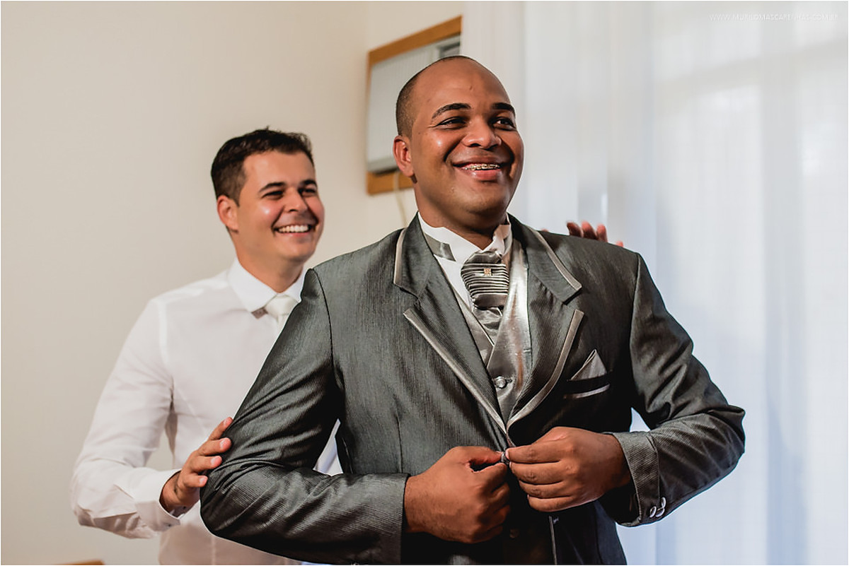 Padrinho ajuda o noivo a colocar o paletó