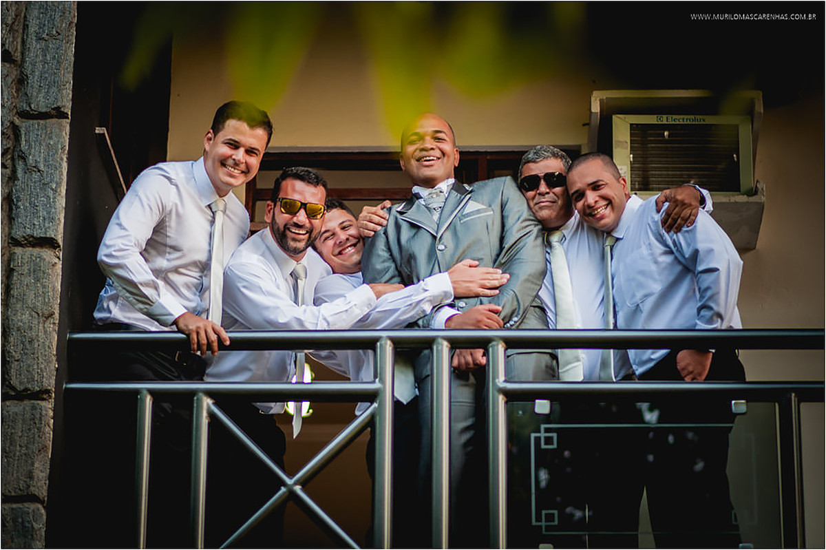 Padrinhos abraçam o noivo pronto, na sacada da varanda