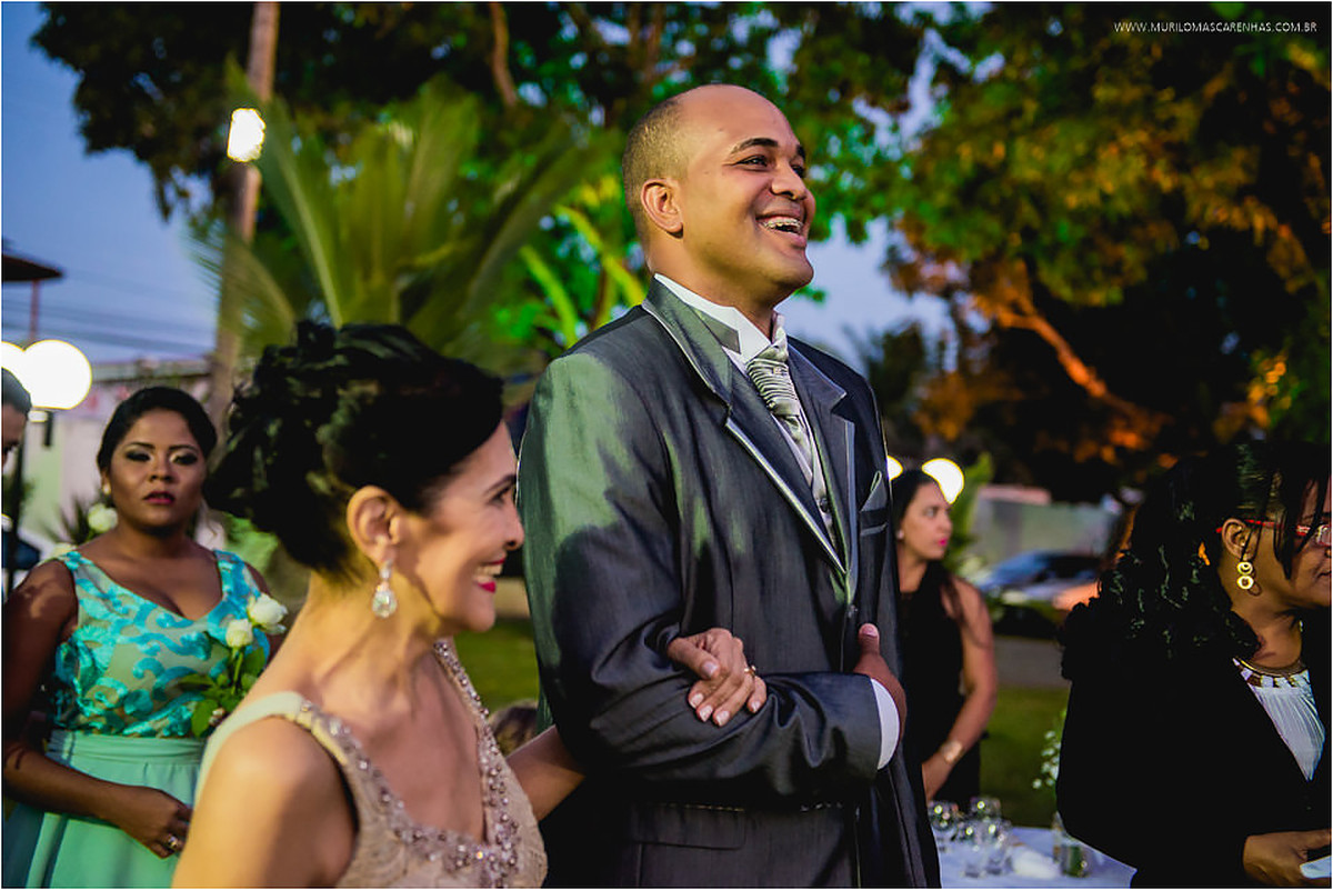 Noivo e sua mãe entram sorridentes na cerimônia