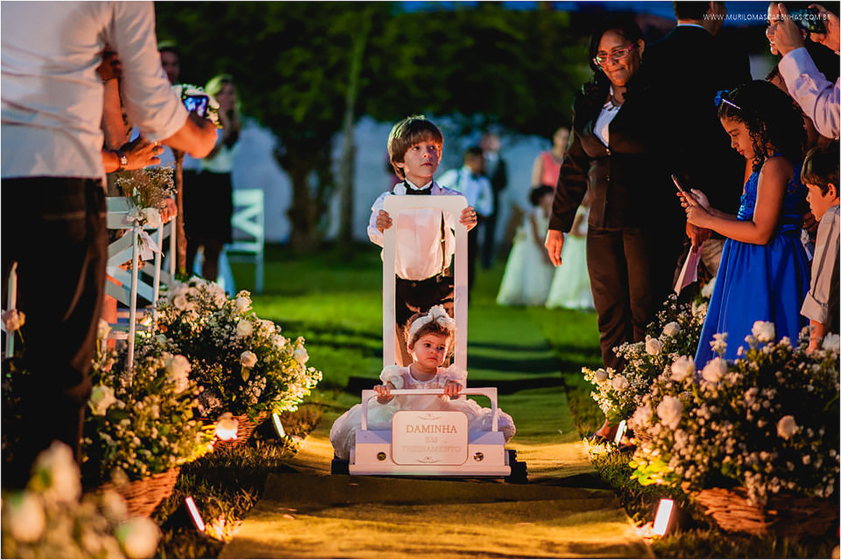 Daminha em treinamento é trazida num carrinho de madeira pelo pajem no corredor da cerimônia