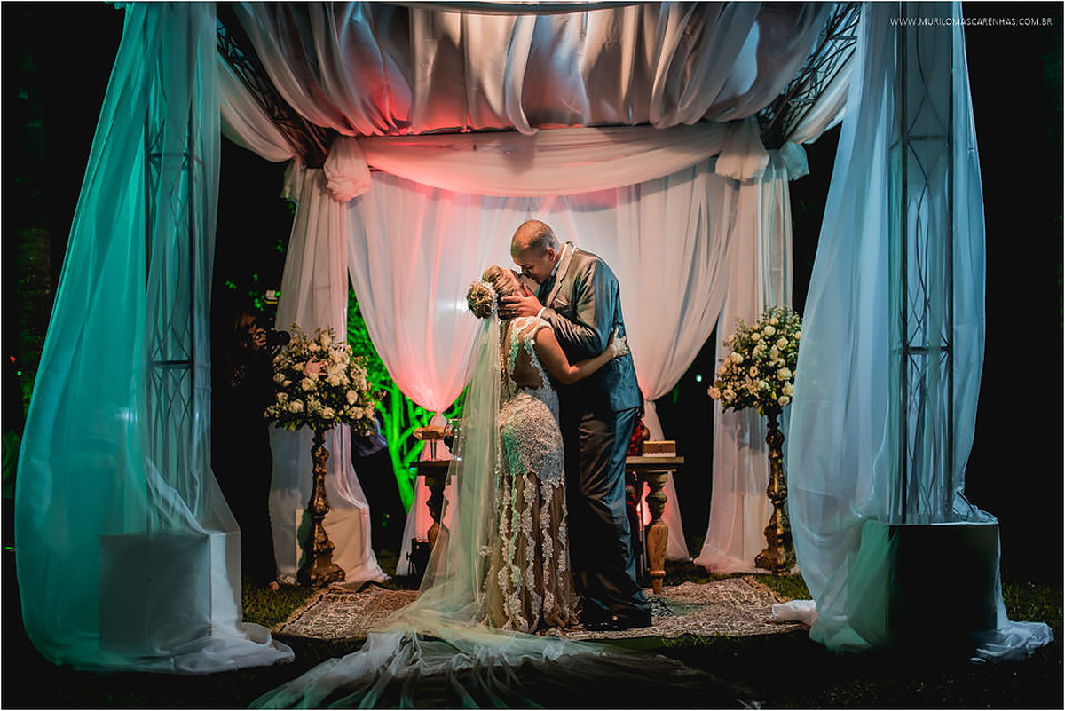 Beijo dos noivos na tenda do altar ao ar livre