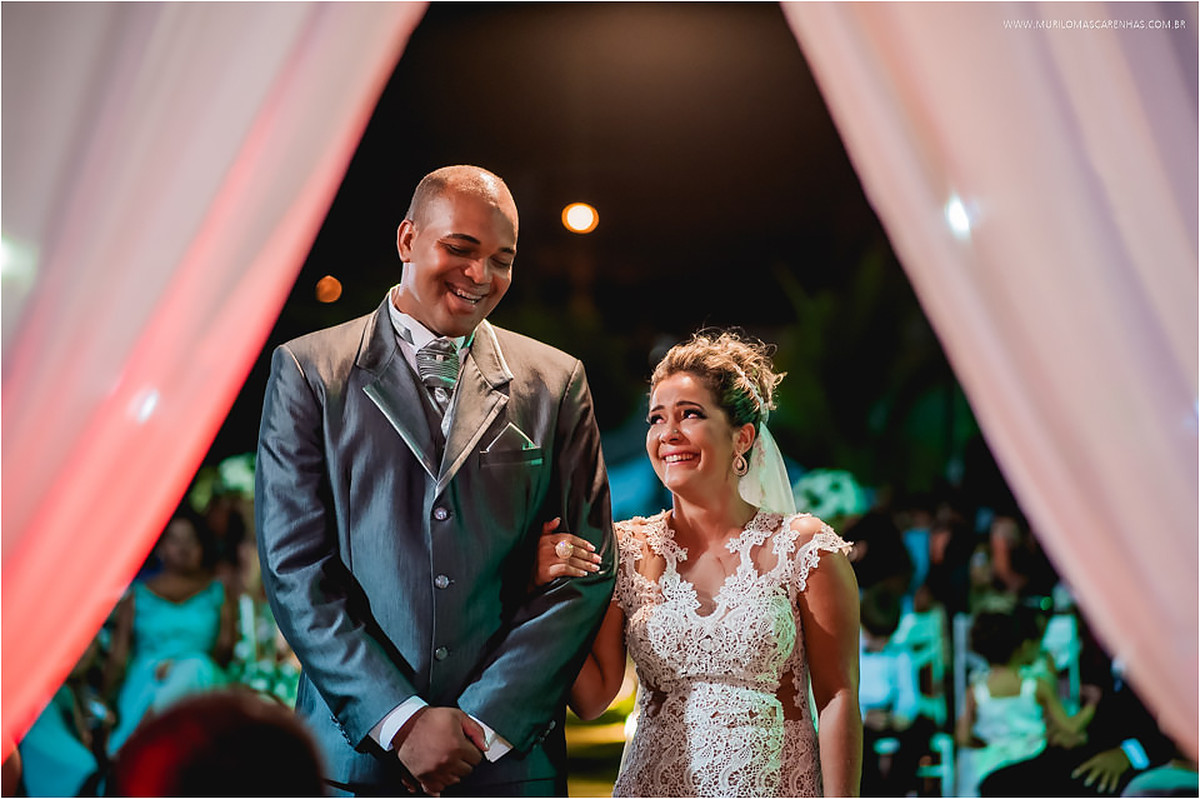 Noiva observa o noivo e sorriem juntos