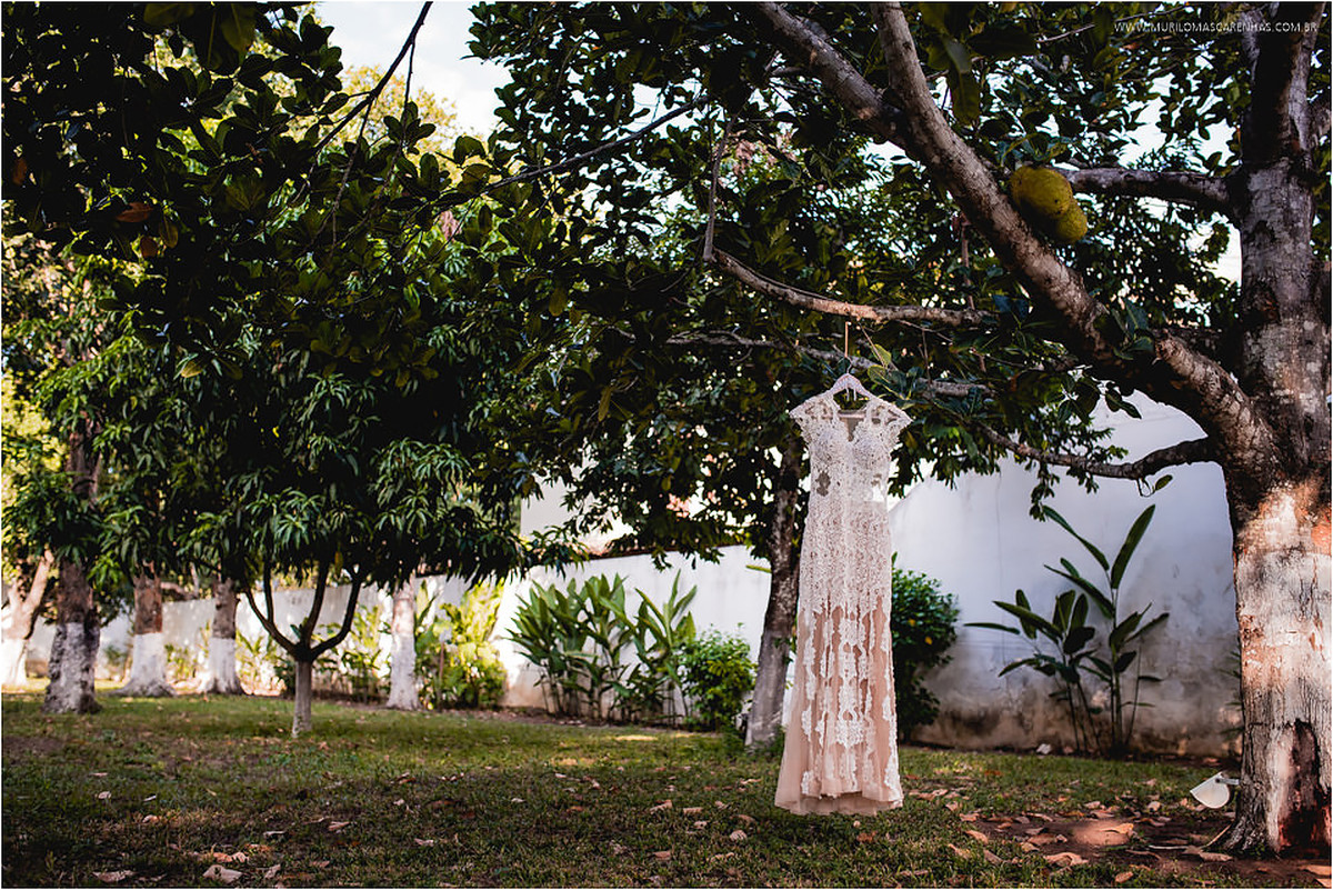 Vestido rendado da noiva pendurado numa árvore do jardim