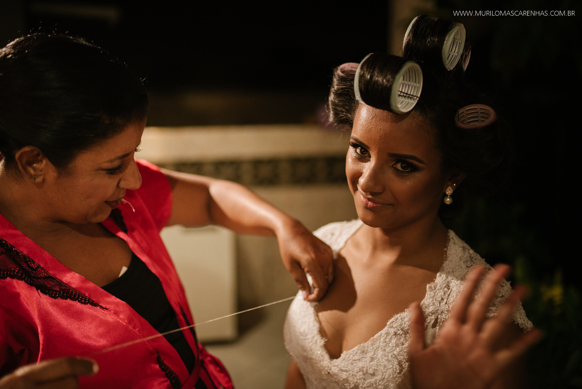 Mãe da noiva costurando o vestido no corpo da filha. Noiva de Bobs