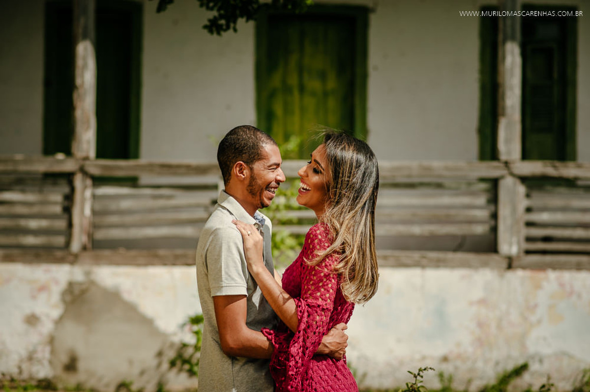 Noivos sorriem abraçados em frente ao casarão antigo