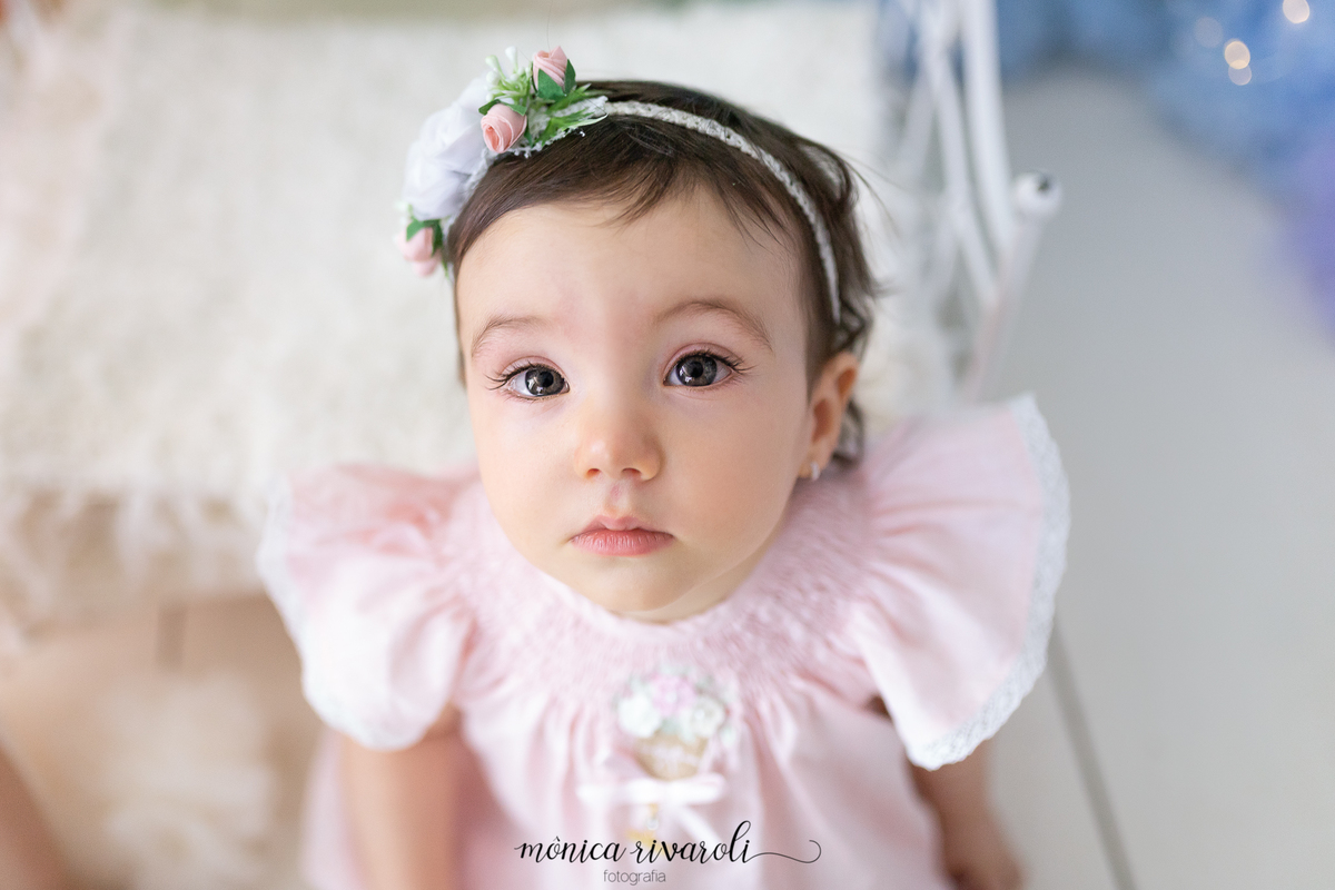A foto foi tirada de cima para baixo, a bebê está olhando para a câmera. Ela tem uma tiara com flores na cabeça
Ensaio Smash The Cake
Fotografado por Mônicas Fotografia em Maringá-PR