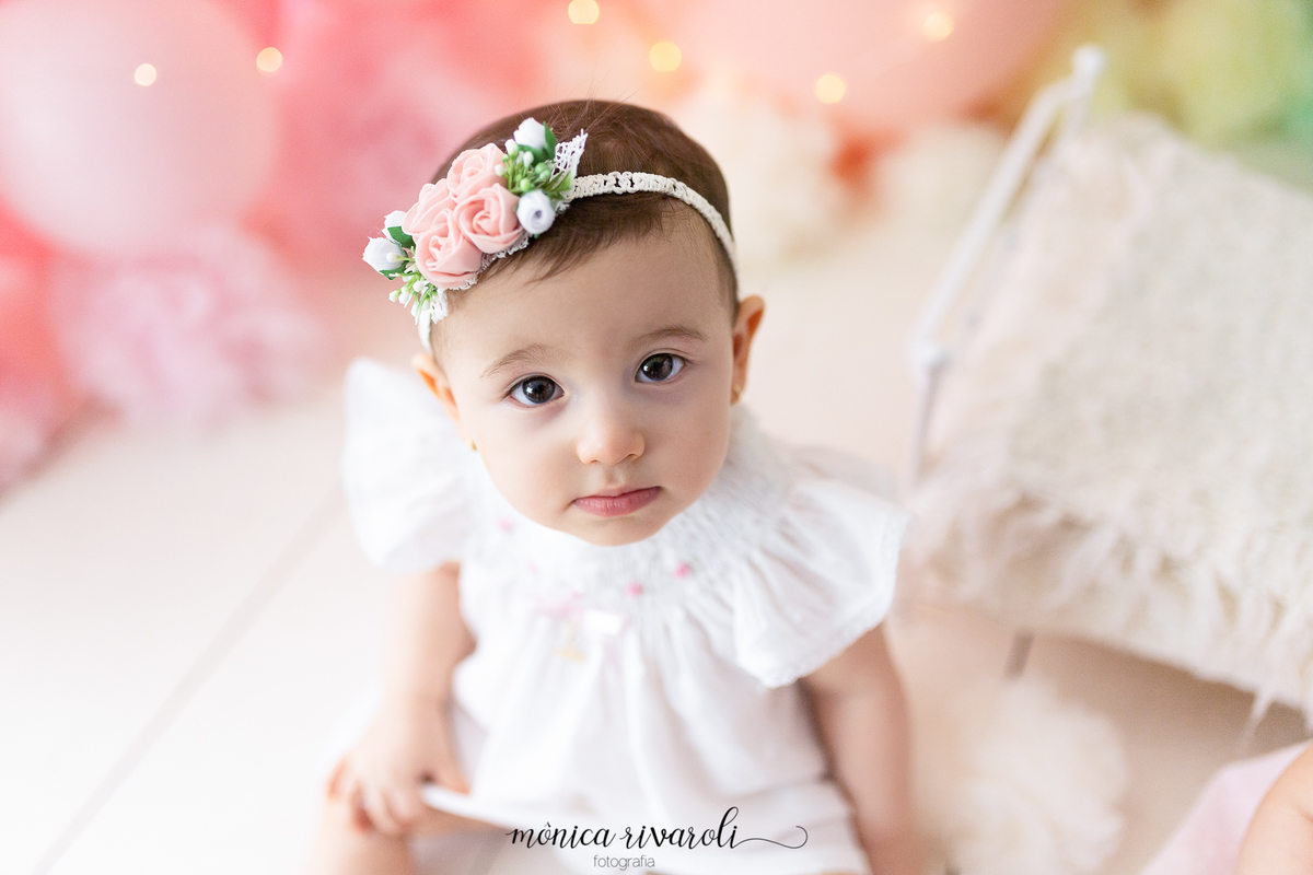 A foto foi tirada de cima para baixo, a bebê está olhando para a câmera e uma das mãos está segurando o vestido
Ensaio Smash The Cake
Fotografado por Mônicas Fotografia em Maringá-PR
