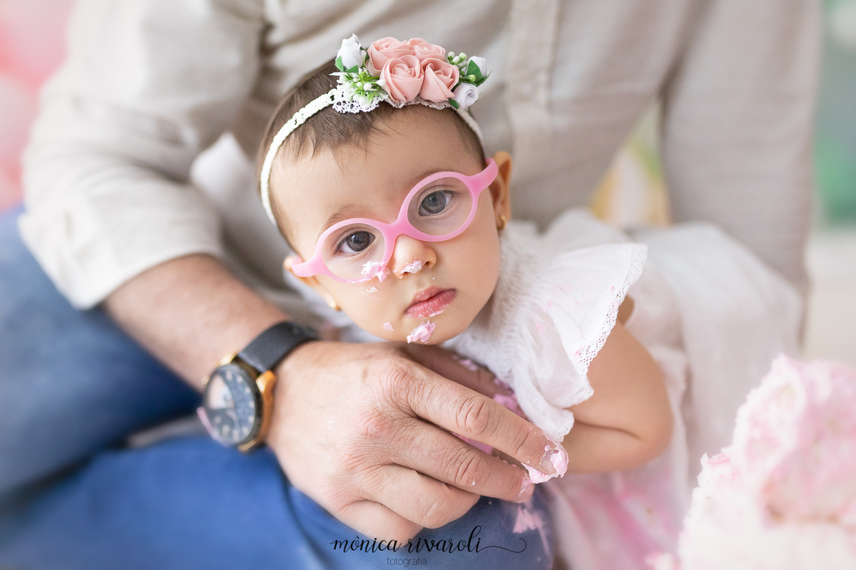 Na foto aparece a bebê apoiada na perna e na mão do pai, que está sentado. Ela está com o rosto lambuzado de chantilly
Ensaio Smash The Cake
Fotografado por Mônicas Fotografia em Maringá-PR