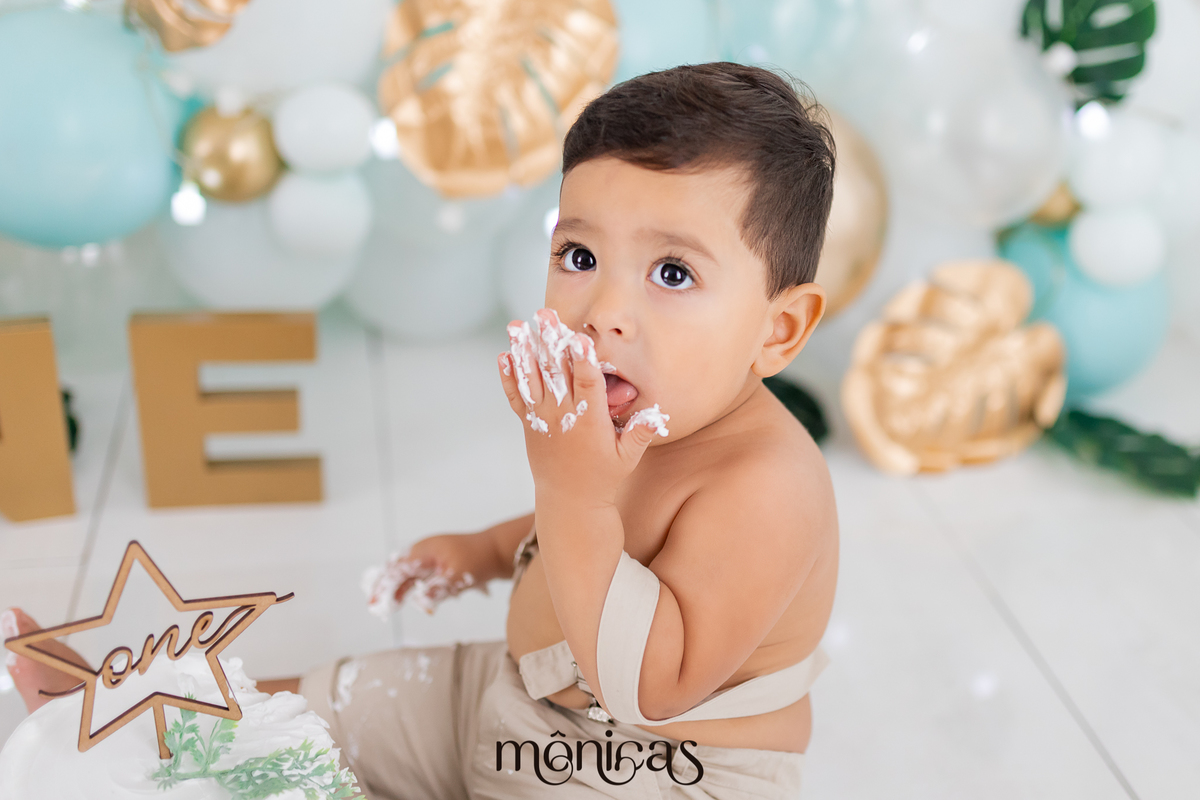 No cenário de Smash, o bebê está perto do bolo com as mãos sujas de chantilly. Uma mão está próxima a boca e o bebê está experimentando o bolo.
Fotografado por Mônicas Fotografia em Maringá-PR