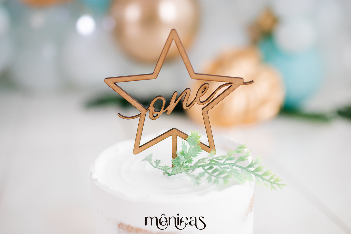 A foto mostra o topo de um bolo branco, com uma estrela e dentro está escrito 