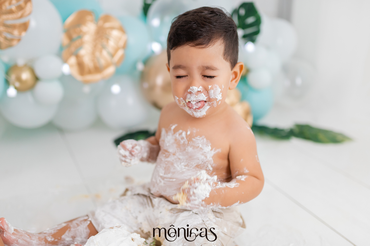 No cenário de Smash, o bebê está todo lambuzado de chantilly, com os olhos fechados e a boca meio aberta enquanto sente o gosto do bolo.
Fotografado por Mônicas Fotografia em Maringá-PR