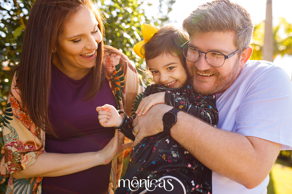 A família brinca. A fila mais velha está no colo do pai enquanto a mãe faz cócegas e todos sorriem