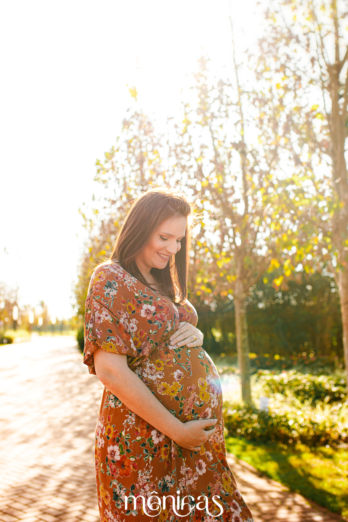 Uma foto na vertical, a gestante olha para seu bebê na barriga e sorri 