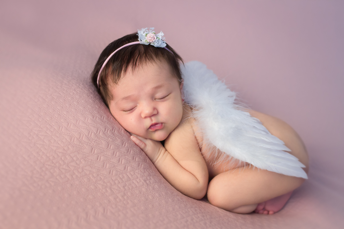 dormindo com uma asinha de anjo num tecido lindo e esticado rosa no click da fotógrafa recém nascido newborn Mônica Rivaroli, a linda Gabriela descansa num sono gostoso