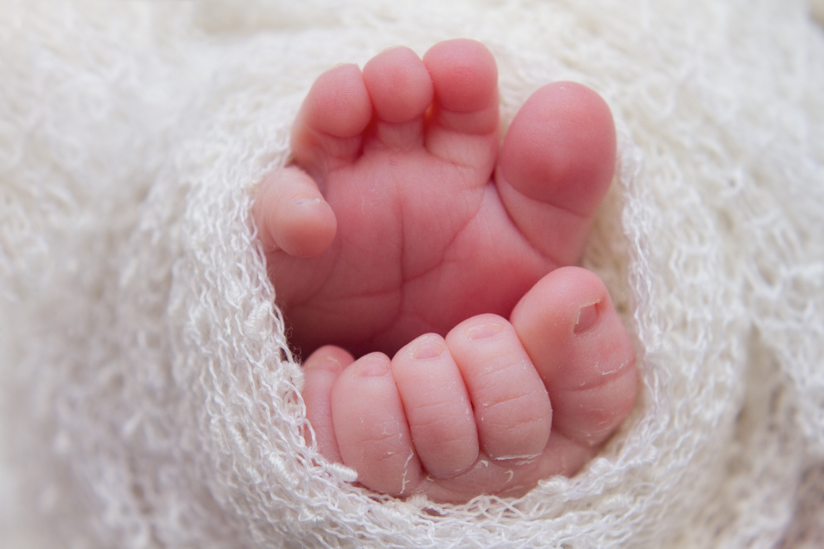 Os pezinhos gordinhos enrolados em um tecido bem fofinho