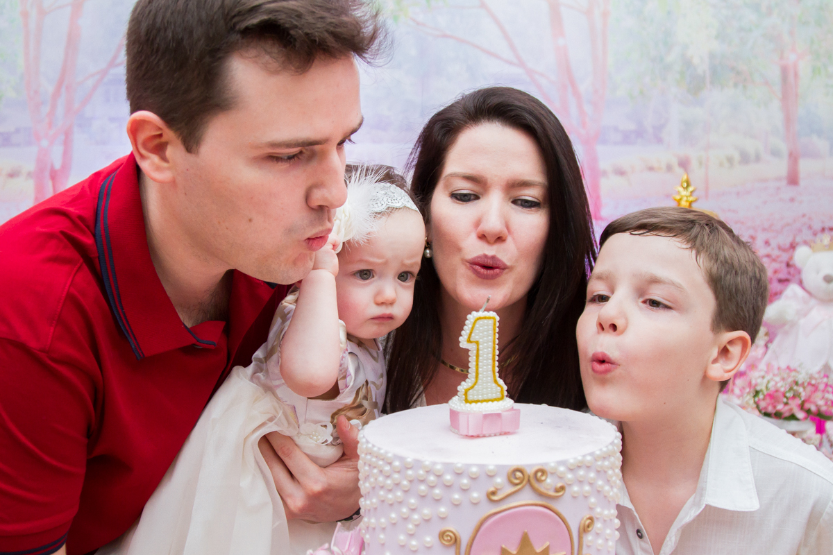 Eduarda, mamãe, papai e seu irmão assoprando as velinhas