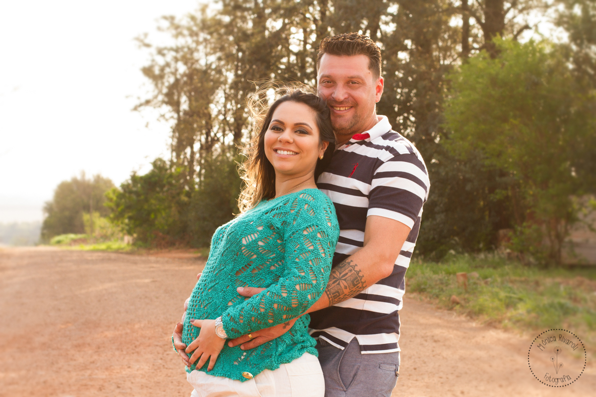 Em uma fotografia contra luz, a gestante Thais está encostada no esposo que segura a barriga dela