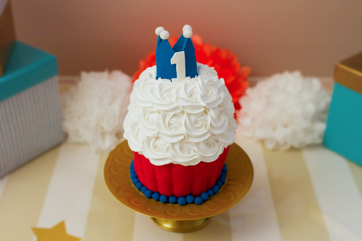 Detalhe do bolo do smash the cake. O bolo tem detalhes em vermelho, azul e parece um cupcake gigante