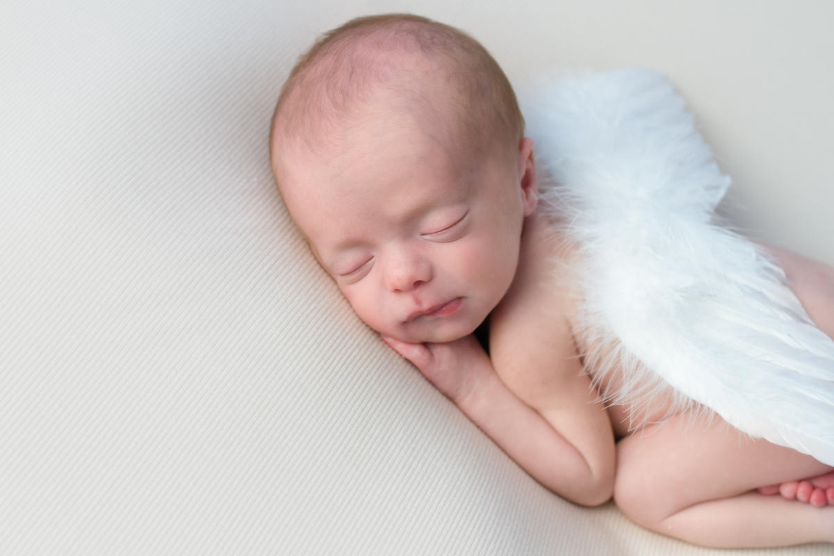 Ainda com a asinha de anjo e uma manta bege, a fotógrafa Mônica Rivaroli faz um close no lado do bebê