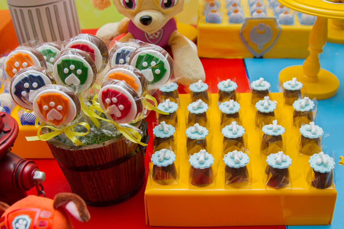 Foto do docinho de chocolate com um ossinho em cima e o pote de pirulitos do lado