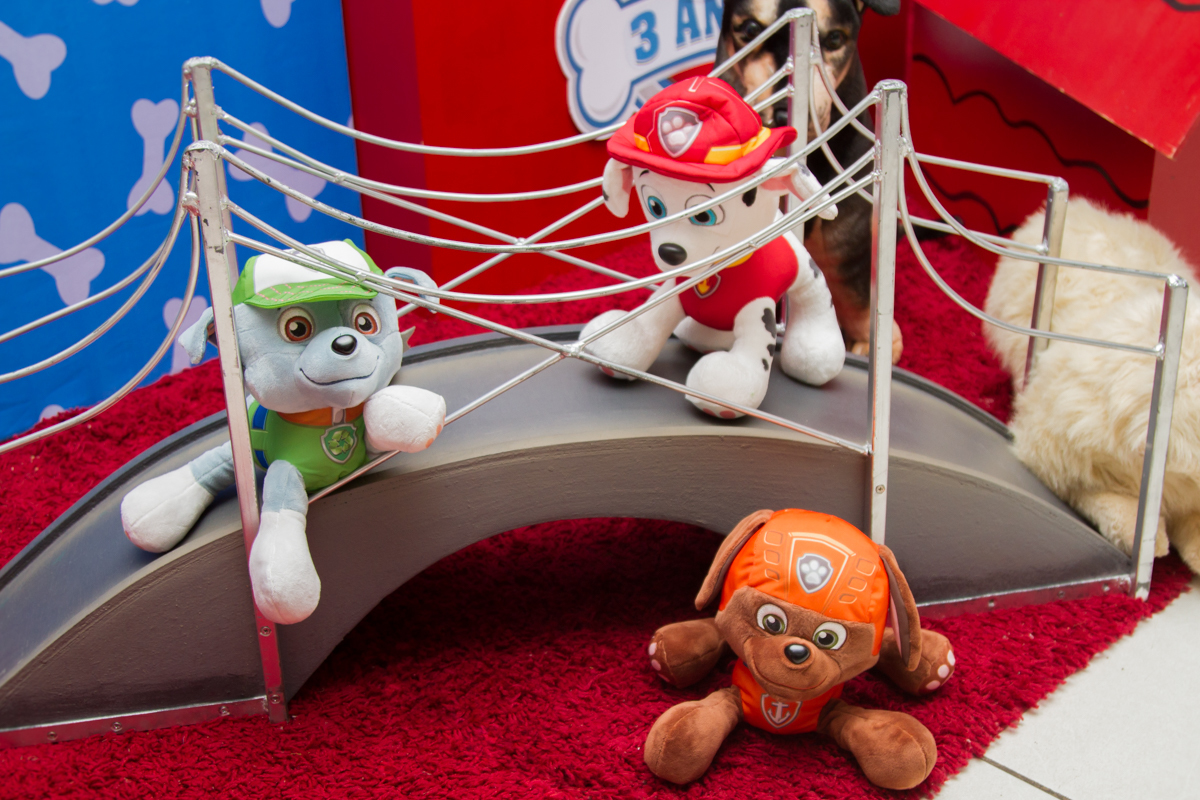 Um close em três cachorrinhos de pelúcia que estão em uma mini ponte