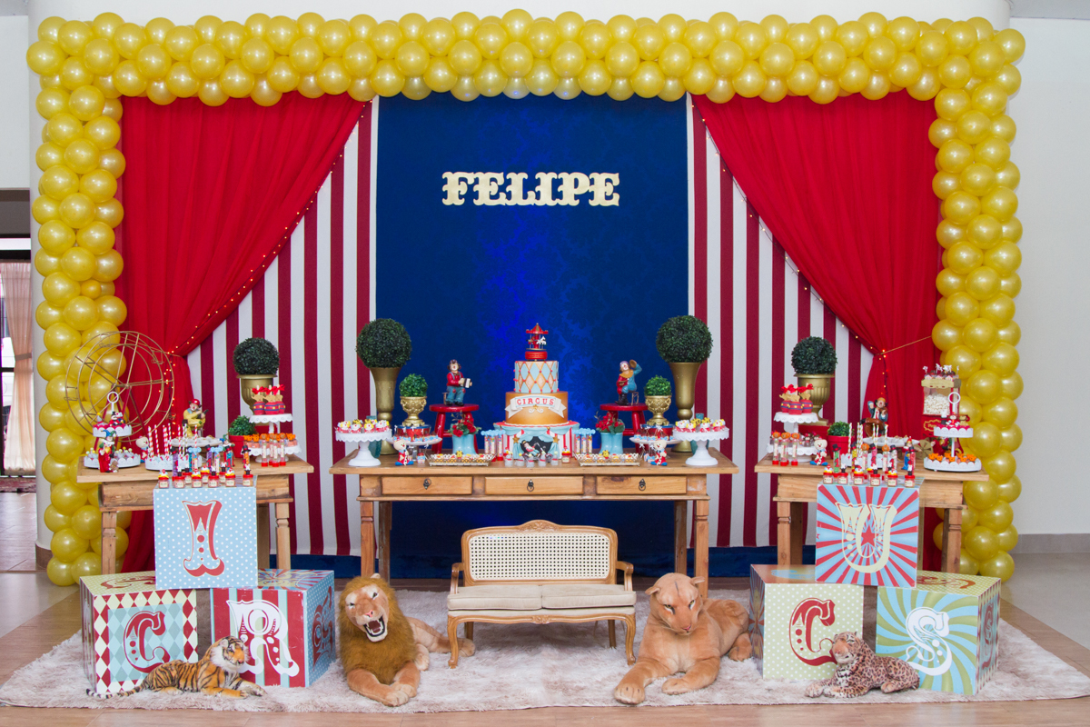 Outra foto da mesa inteira com bexigas em volta e em baixo pelúcias de leões 