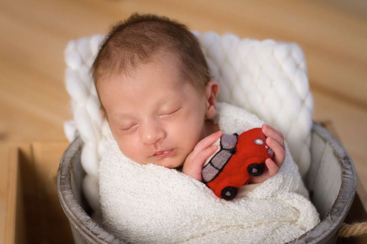 Enroladinho em um paninho bem fofinho, o Dudu segura um carrinho réplica de um mini cooper. O papai dele ama carros!