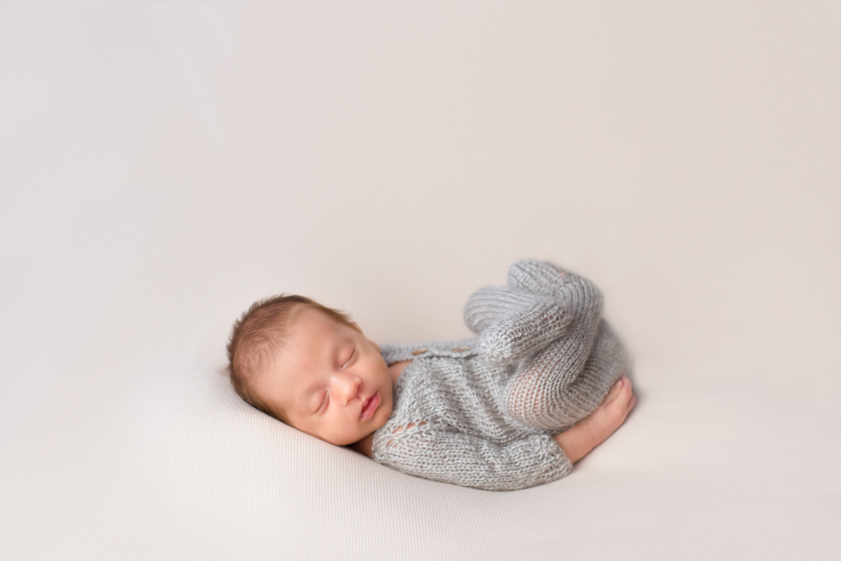 Vestido com um mamacãozinho cinza de tricô, ele dorme bem gostoso com as perninhas para cima