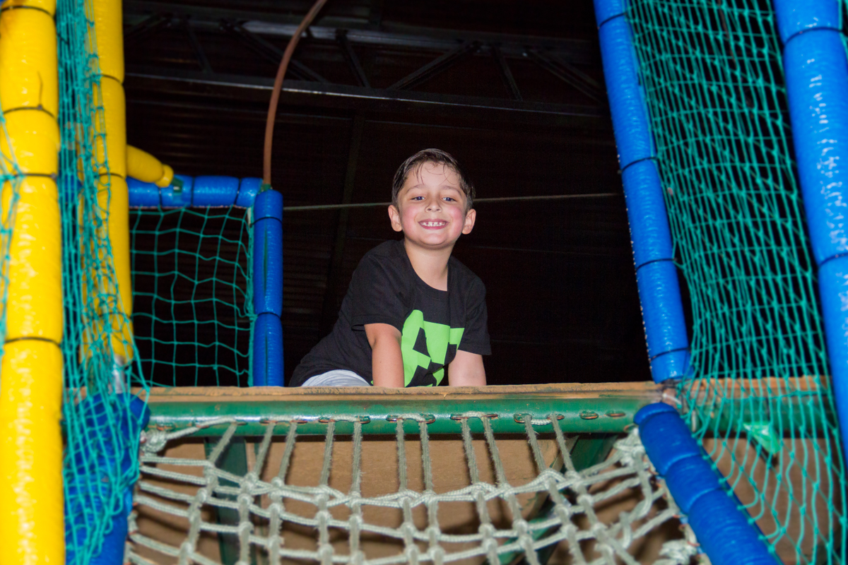 Gabriel sorrindo para a foto em cima de um brinquedo 