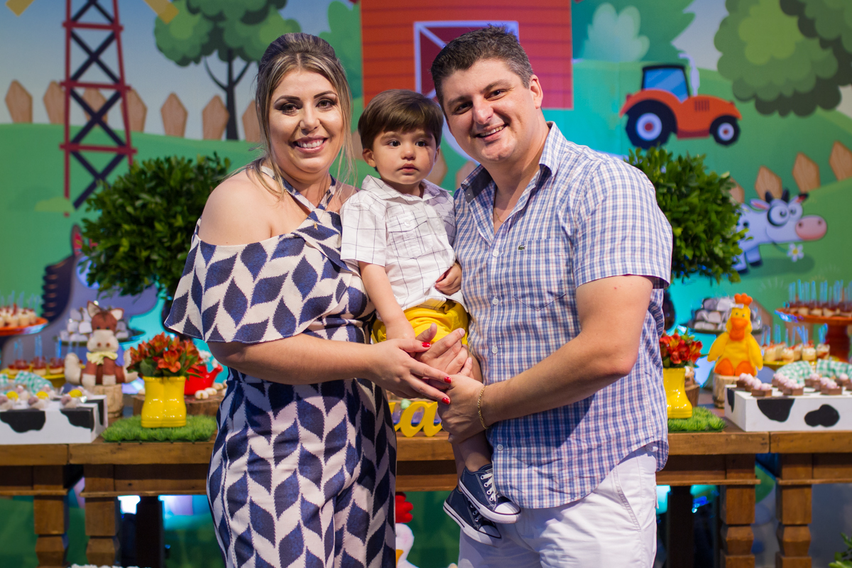 Foto dos papais com o Edu na frente da mesa 