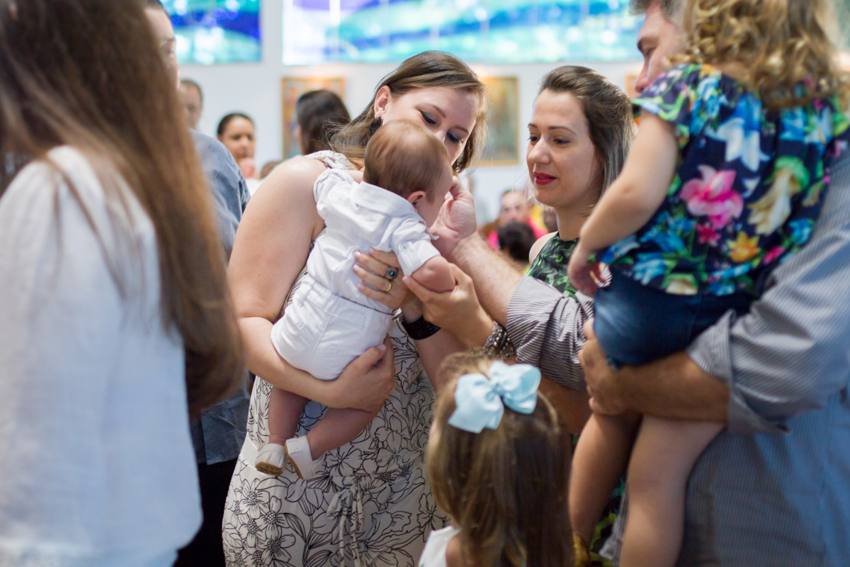 Fotinha da madrinha com o padrinho fazendo o sinal da cruz no Miguel