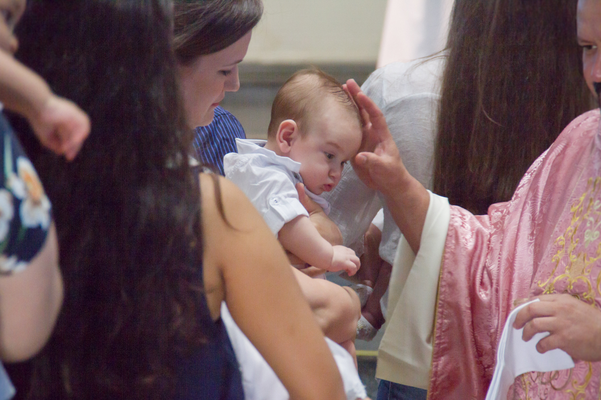 Close no padre fazendo o sinal da cruz no Miguel 