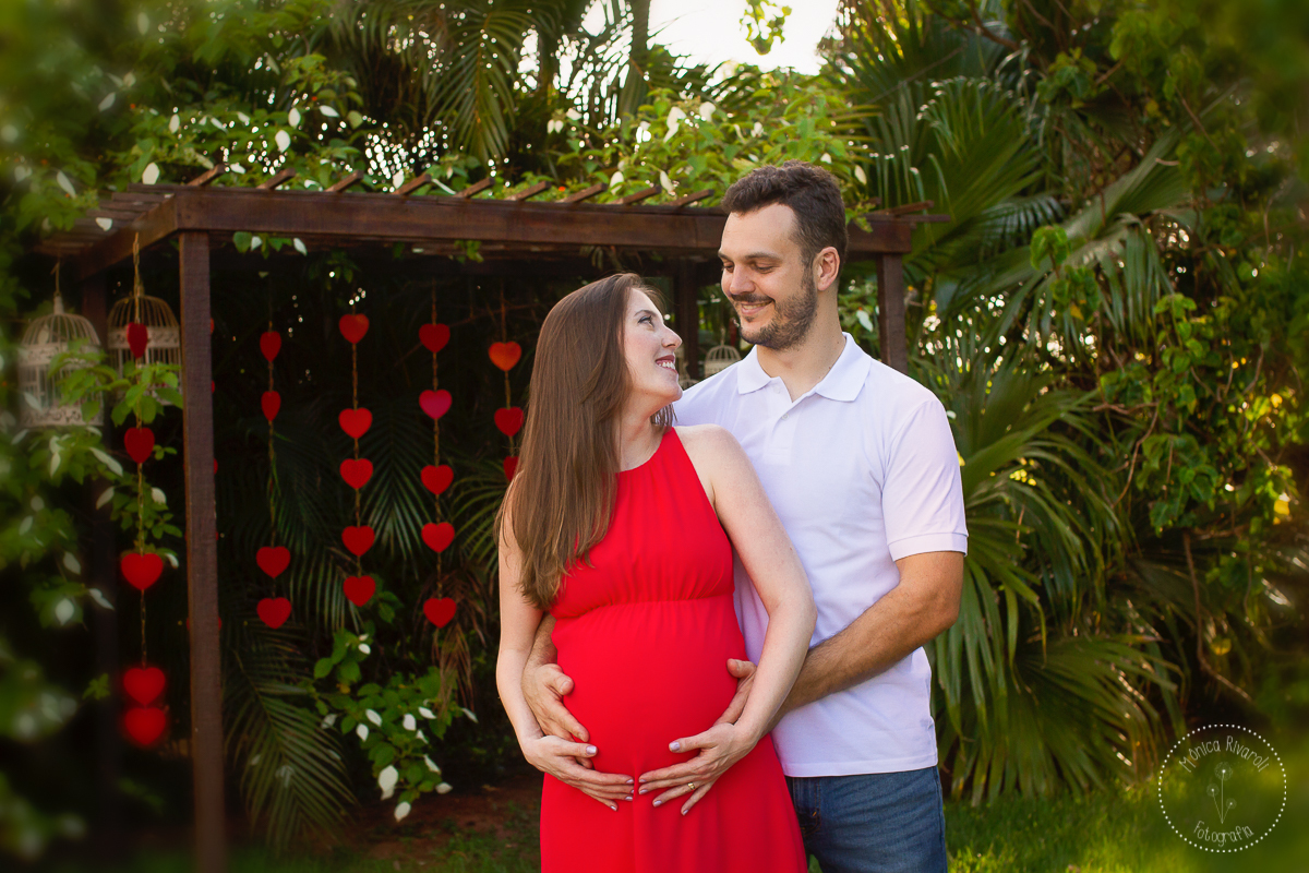Foto do papai e da mamãe sorrindo olhando um para o outo e com a mão na barriga
