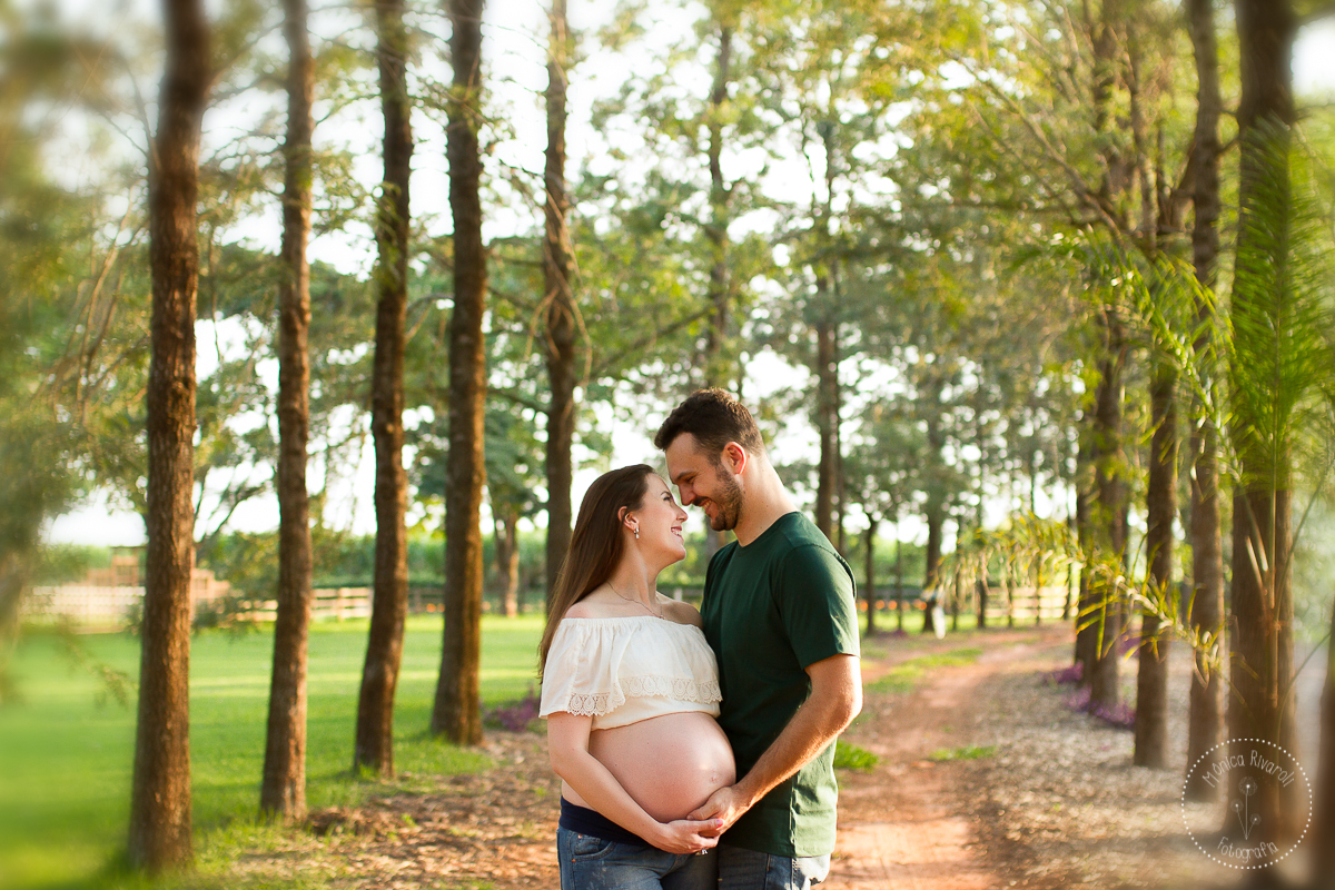 Papai e mamãe em uma estrada, olhando um para o outro e com a mão na barriga