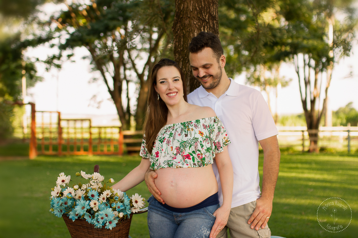 Papai atrás da mamãe, segurando sua barriga e olhando para o Pedro