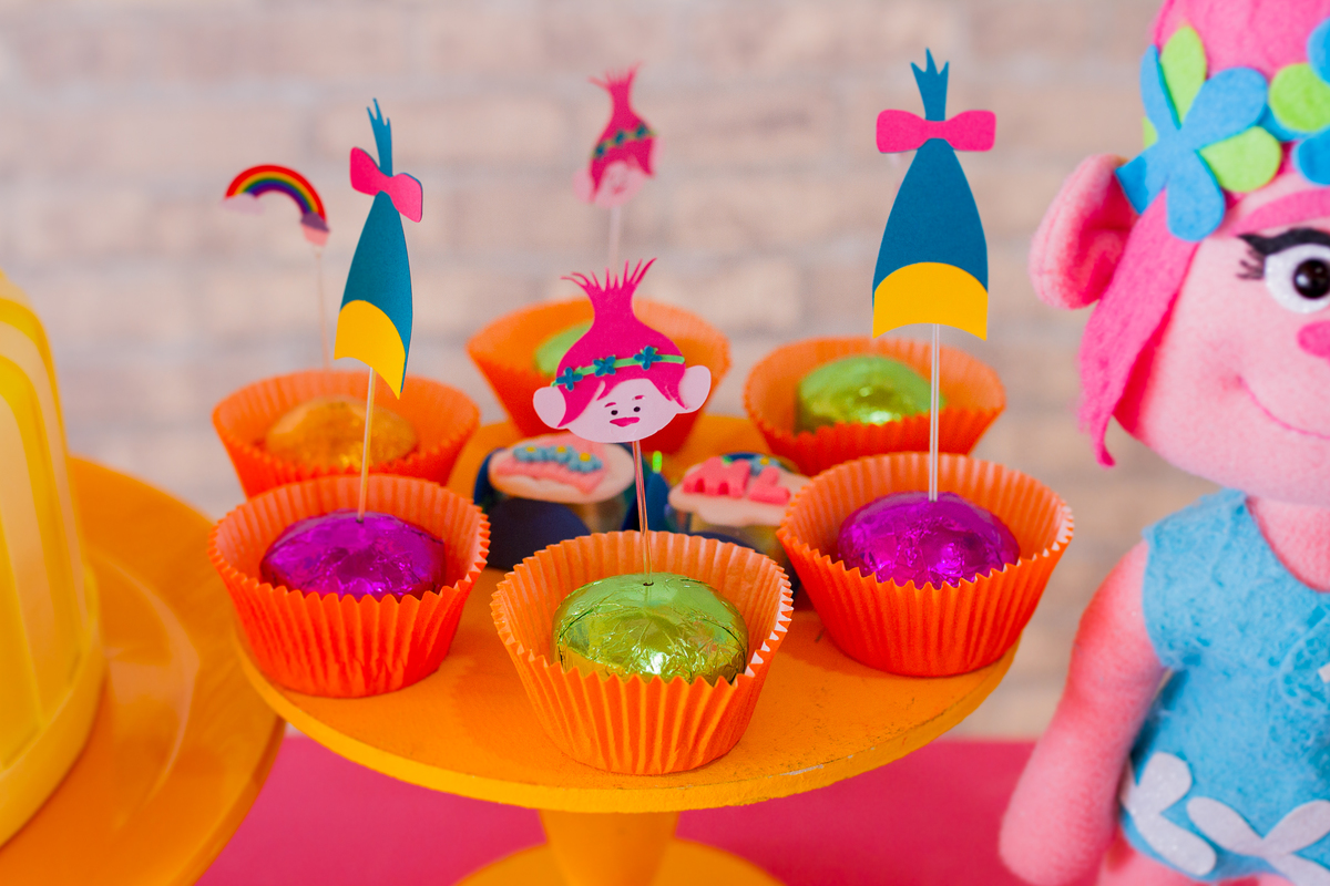 Doces coloridos com palitinho com desenhos dos trolls em cima