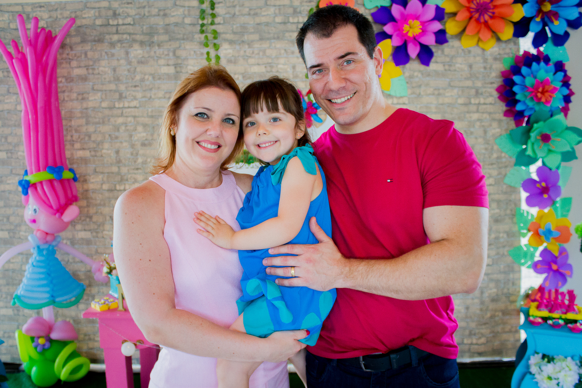 A Malu esta no colo da mamãe, do ladinho do papai, sorrindo para a foto