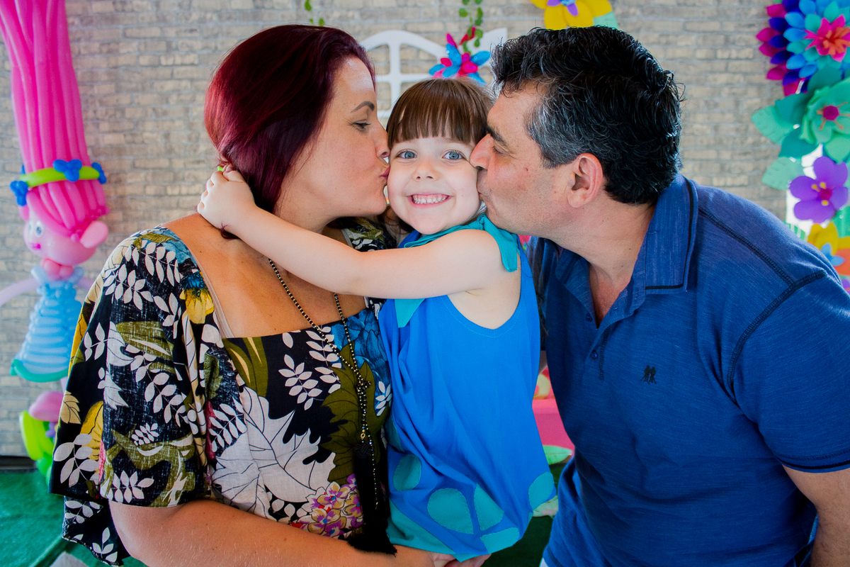 A Malu esta no colo da titia recebendo um beijo na bochecha dela e do titio