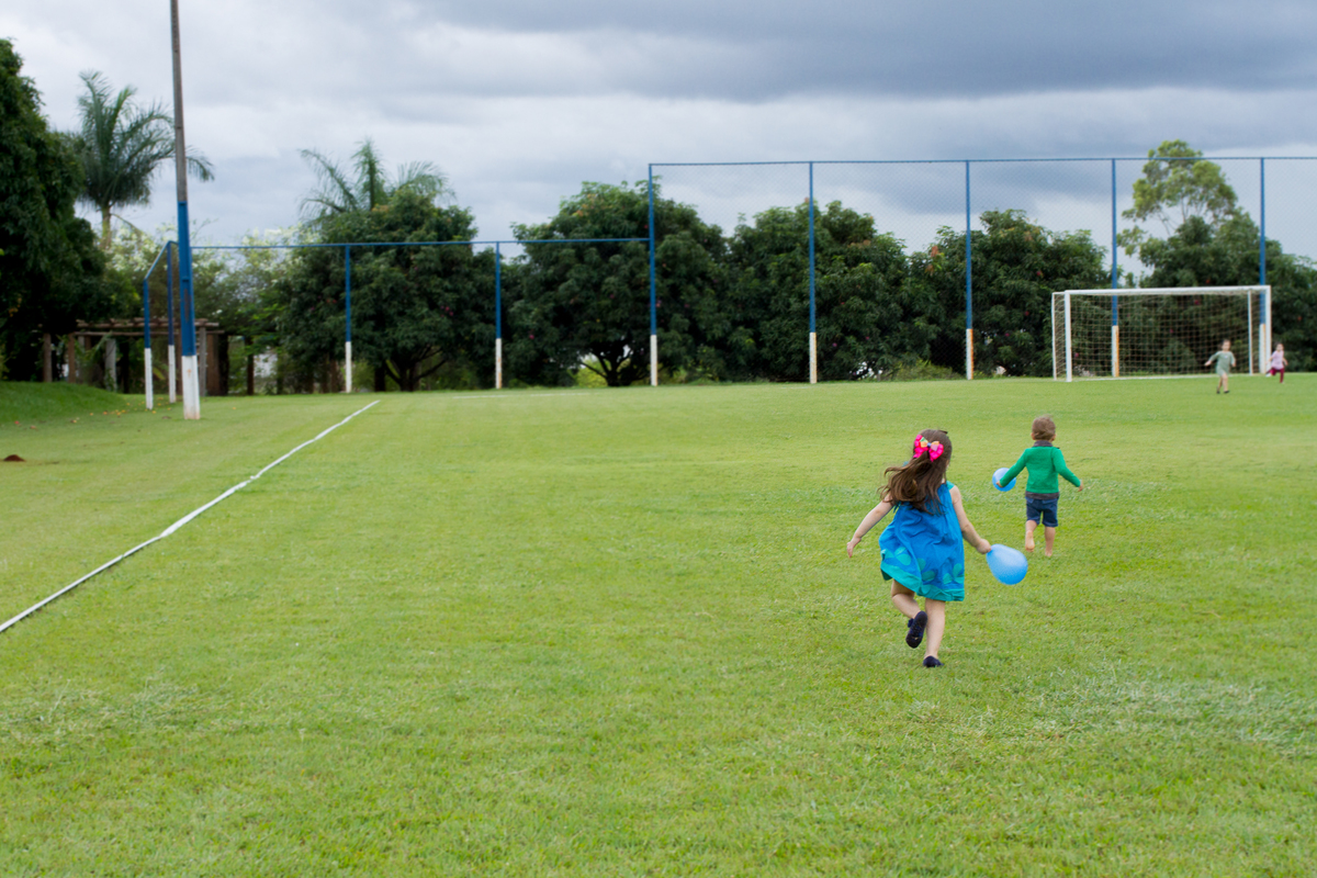 Imagem aberta da Malu e do seu amiguinho correndo no campo de futebol