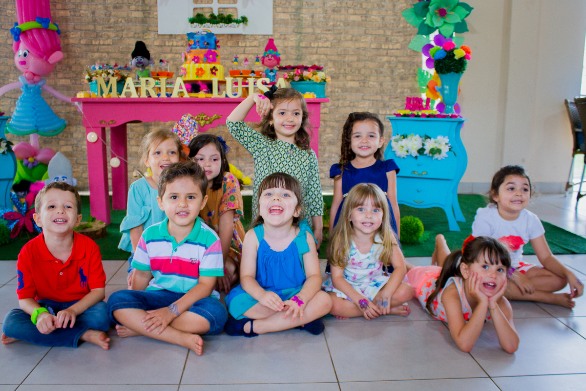 As crianças estão sentadas no chão pára tirar uma foto bem bonita com a Malu