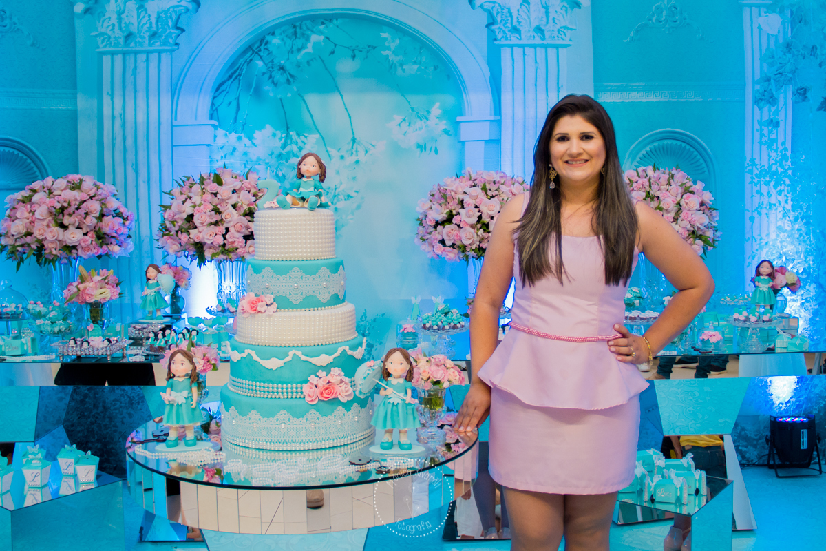 A mamãe Ju posa para uma foto ao lado do bolo